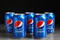 MYKOLAIV, UKRAINE - FEBRUARY 9, 2021: Many cans of Pepsi on table against black background