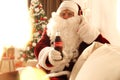 MYKOLAIV, UKRAINE - JANUARY 18, 2021: Santa Claus listening to music with headphones at home, focus on Coca-Cola bottle in his Royalty Free Stock Photo