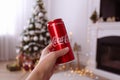 MYKOLAIV, UKRAINE - JANUARY 13, 2021: Woman holding can of Coca-Cola in room with Christmas tree, closeup