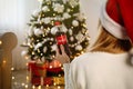 MYKOLAIV UKRAINE - January 01 2021: Woman in Santa hat with bottle of Coca-Cola against blurred Christmas tree at home back