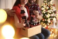 MYKOLAIV, UKRAINE - JANUARY 27, 2021: Young couple holding crate with bottles of Coca-Cola in room decorated for Christmas,