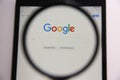 MYKOLAIV, UKRAINE - OCTOBER 30, 2020: Looking through magnifying glass at screen with Google search bar on white background