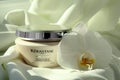 MYKOLAIV, UKRAINE - SEPTEMBER 07, 2021: Kerastase hair care mask and beautiful orchid flower on white fabric