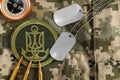 MYKOLAIV, UKRAINE - SEPTEMBER 26, 2020: Metal military ID tags near Ukrainian army patch, bullets and compass on camouflage Royalty Free Stock Photo