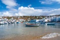 Mykonos, Greece - May 04, 2010: boats on sea water. Sea beach on cloudy blue sky. Houses on mountain landscape with