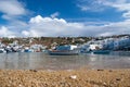 Fishing boats on sea beach in Mykonos, Greece. Sea village on cloudy sky. White houses on mountain landscape with nice