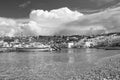 Mykonos, Greece - May 04, 2010: sea beach with boats on cloudy blue sky. Houses on mountain landscape by sea