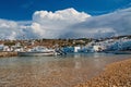 Mykonos, Greece - May 04, 2010: sea beach with boats on cloudy blue sky. Houses on mountain landscape by sea