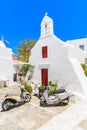 MYKONOS TOWN, GREECE - MAY 16, 2016: Two scooters parked in front of a typical white church with red doors in Mykonos town, Royalty Free Stock Photo