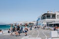 People walking on a street in Little Venice past the sea in Hora Mykonos Town, Mykonos, Greece