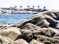 Mykonos windmills in a row on background, rocks on beach on foreground, Greece Royalty Free Stock Photo