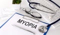 MYOPIA text on white paper on white background. stethoscope ,glasses and keyboard