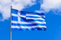 The national flag of Greece looks like 9 white and blue stripes with a cross on a background of blue sky in the summer afternoon. Royalty Free Stock Photo