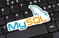 MySQL logo sticker laying on a laptop keyboard, object closeup, nobody. My SQL database technology symbol, website backend