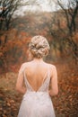 Mysterious, beauty young woman in white dress with open back. bridal hairstyle