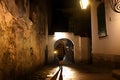 Mysterious blonde woman in elegant retro coat with old oil lantern walking in old French street in Royalty Free Stock Photo