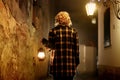 Mysterious blonde woman in elegant retro coat with old oil lantern walking in old French street in Royalty Free Stock Photo