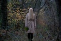 Mysterious female standing in a forest with her long blonde hair covering her face