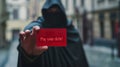 Mysterious figure holding red debt card in urban alley