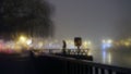 A mysterious figure standing by street lights next to a river on a misty winters night. With a blurred, bokeh, out of focus edit Royalty Free Stock Photo