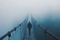 Mysterious figure strolling on a bridge disappearing into the fog, centered on the pathway Royalty Free Stock Photo