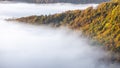 Mysterious fog rising over a valley with a colorful autumn forest at sunrise Royalty Free Stock Photo