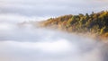 Mysterious fog rising over a valley with a colorful autumn forest at sunrise Royalty Free Stock Photo