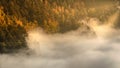 Mysterious fog rising over a valley with a colorful autumn forest at sunrise Royalty Free Stock Photo