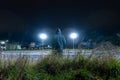 A mysterious hooded figure, with back to camera. Looking out across an industrial estate and street lights on a winters night Royalty Free Stock Photo