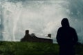A mysterious hooded figure looking at a ruined farm building on top of a hill. With a grunge vintage edit