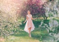 Mysterious lady with dark gathered hair in a light delicate peach dress walks in the blooming garden, the spring fairy Royalty Free Stock Photo