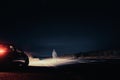 A mysterious lone figure next to a car, parked on the side of the road, on a summers night. Standing in the middle of a road