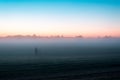 A mysterious lone ghostly, figure standing in a field just before sunrise. On a misty summers morning.