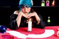 Mysterious magnificent beautiful woman fortune teller in black dress with a candle and cards on table, dark witch trying to read Royalty Free Stock Photo