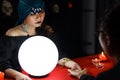 Mysterious magnificent beautiful woman fortune teller in black dress with magical crystal ball holding and looking at  the Royalty Free Stock Photo