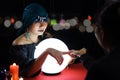 Mysterious magnificent beautiful woman fortune teller in black dress with magical crystal ball pointing to the customer palm, try