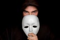 Mysterious man in black hiding his face behind white mask Royalty Free Stock Photo