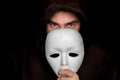 Mysterious man in black hiding his face behind white mask Royalty Free Stock Photo