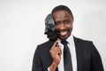 African young man wearing black suit taking off plastic mask revealing face and smiling Royalty Free Stock Photo