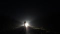 A mysterious man silhouetted against car headlights on a country road on a misty winters night