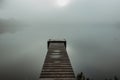 Mysterious morning by lake. Foggy autumn mystery atmosphere. Wooden pier on the pond.Magic mood. Misty fall day. Speechless place