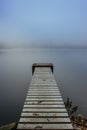 Mysterious morning by lake. Foggy autumn mystery atmosphere. Wooden pier on the pond.Magic mood. Misty fall day. Speechless place