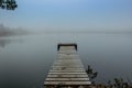 Mysterious morning by lake. Foggy autumn mystery atmosphere. Wooden pier on the pond.Magic mood. Misty fall day. Speechless place