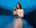 Mysterious mystical girl in a dark night forest with a kerosene lamp in her hands