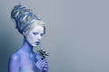 Mysterious perfect woman fashion model with white face, stage makeup and and blue skin on body holds black rose flower on gray