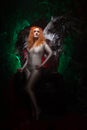 Mysterious plus size red hair girl in skincolor beige outfit with black and white big demon wings on gothic cemetery