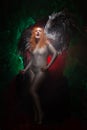 Mysterious plus size red hair girl in skincolor beige outfit with black and white big demon wings on gothic cemetery