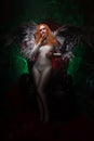 Mysterious plus size red hair girl in skincolor beige outfit with black and white big demon wings on gothic cemetery