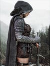 Mysterious Ranger warrior female wearing a hooded cape and leather armor preparing for her journey.