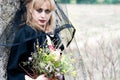 Mysterious sexy blonde woman in a red dress and black cloak, with a black veil on her head. in nature next to an old, almost Royalty Free Stock Photo